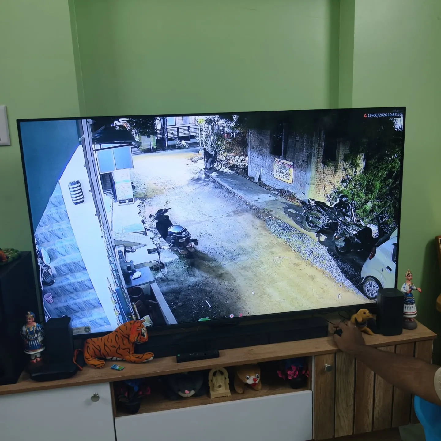 TV screen showing a Cpplus 2MP HD Dual Light camera feed monitoring a residential street lane, outdoor stairs, and parked vehicles.