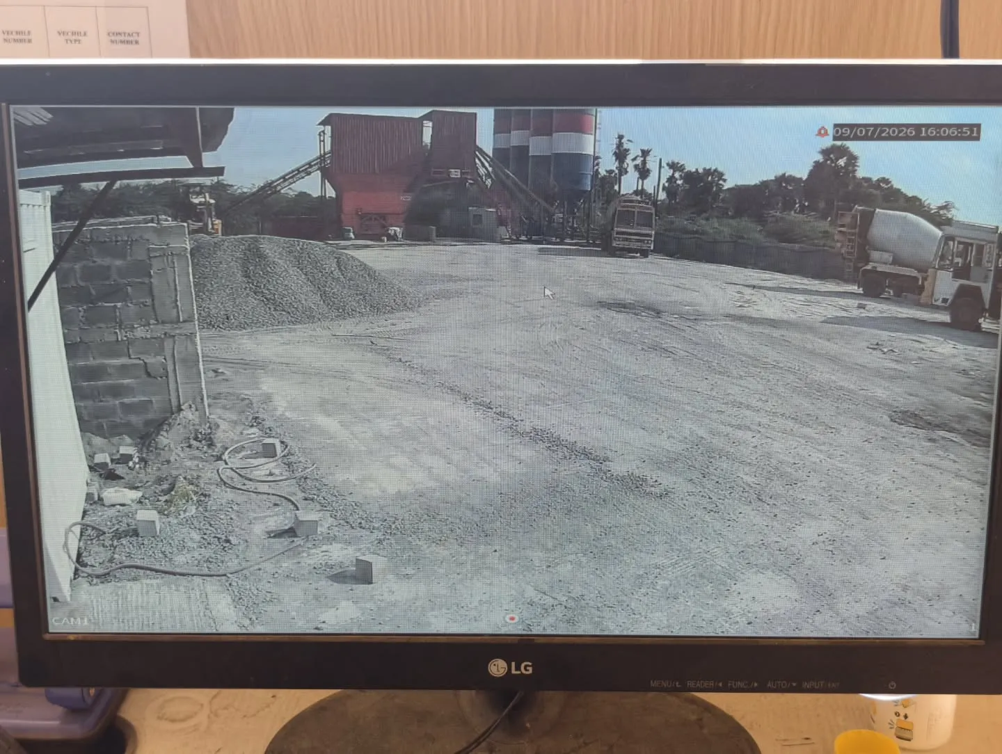 ​A high-definition live video feed from a CP Plus 2MP Dual Light camera tracking concrete mixer trucks and material silos with sharp daytime clarity.