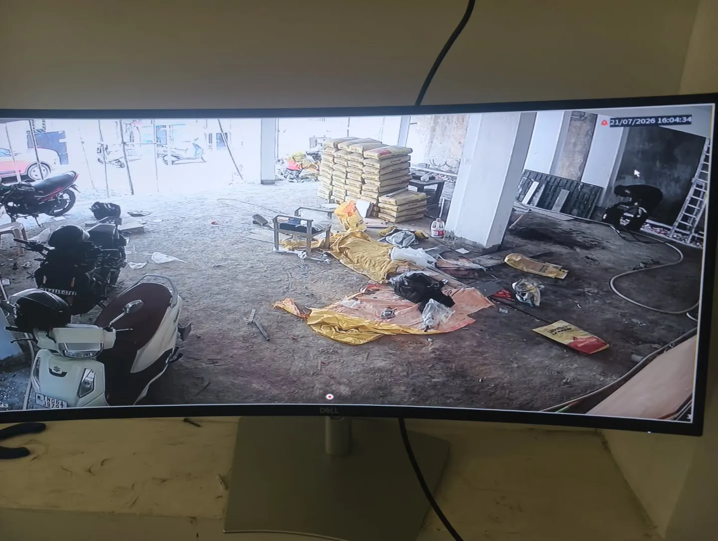 A sharp live monitor display showing the full wide-angle coverage of the ground-floor parking space and stilt area using CP Plus cameras.