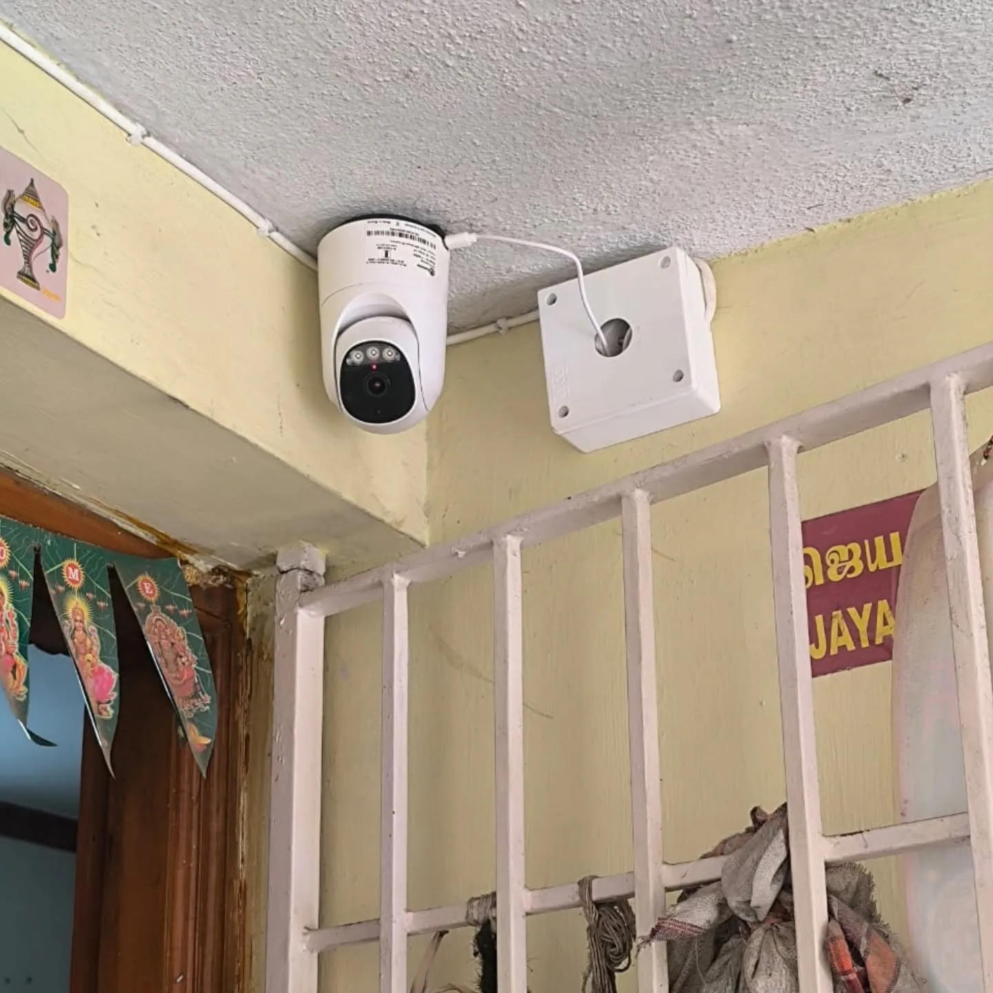 Trueview 3MP indoor robot WiFi pan-tilt camera mounted on ceiling near residential safety grill gate with neat white junction box in Puzhuthivakkam Chennai