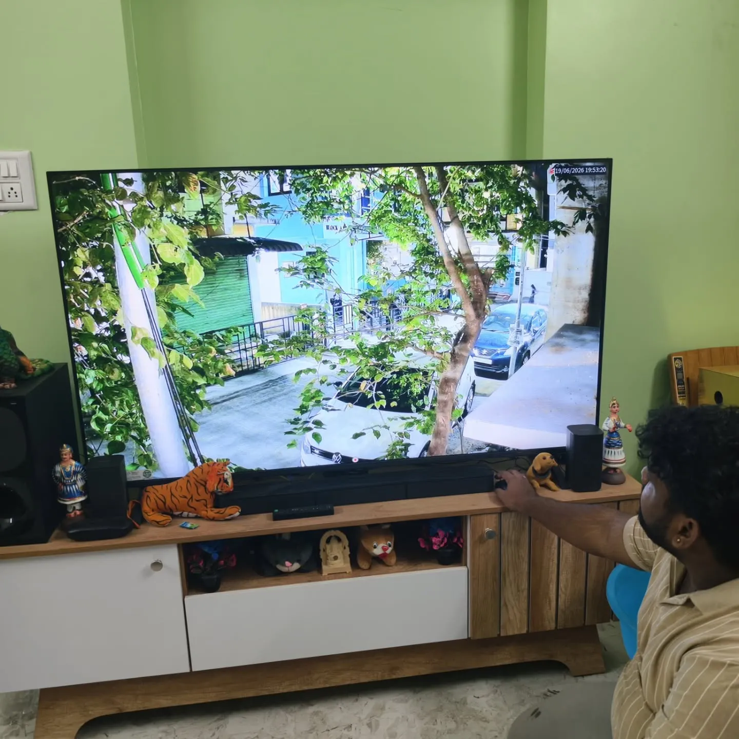 ​A detailed full-frame single-channel live display on a home television screen, showcasing sharp outdoor surveillance footage from a Cpplus 2MP HD Dual Light camera tracking a residential street and parked vehicles.