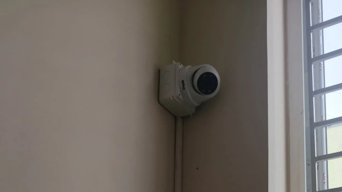 ​A high-angle view of a Gopix 5MP dome camera mounted near a window frame with clean conduit wiring for indoor apartment hallway monitoring.
