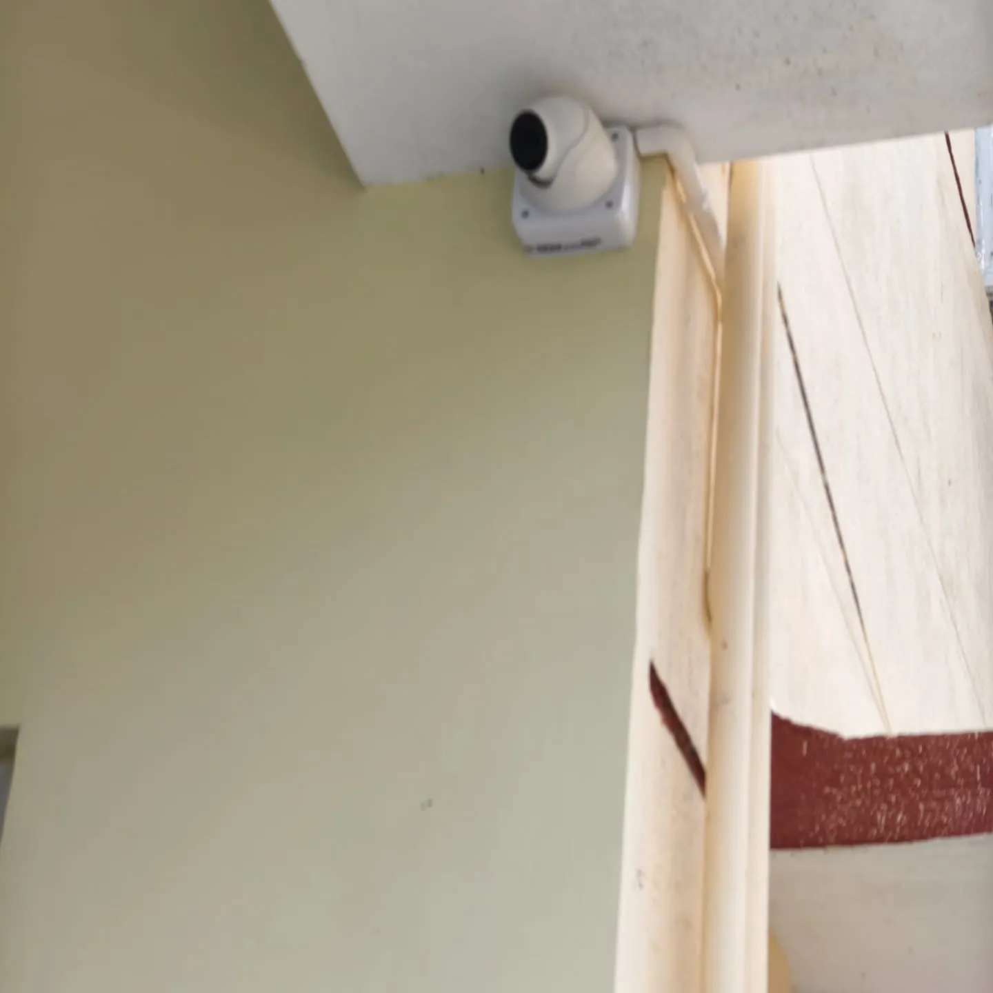 ​A Hikvision 5MP indoor dome camera neatly anchored flush against a ceiling corner with structured PVC casing.