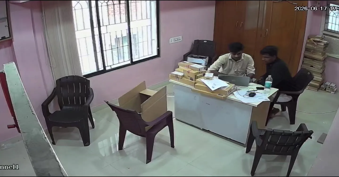 High-angle wide indoor security camera footage from a Dahua 2MP Dual Light camera showing the main reception and service desk area at the Lenovo Service Centre in Velachery, featuring two staff members working at a laptop with customer package boxes neatly stacked on the table.
