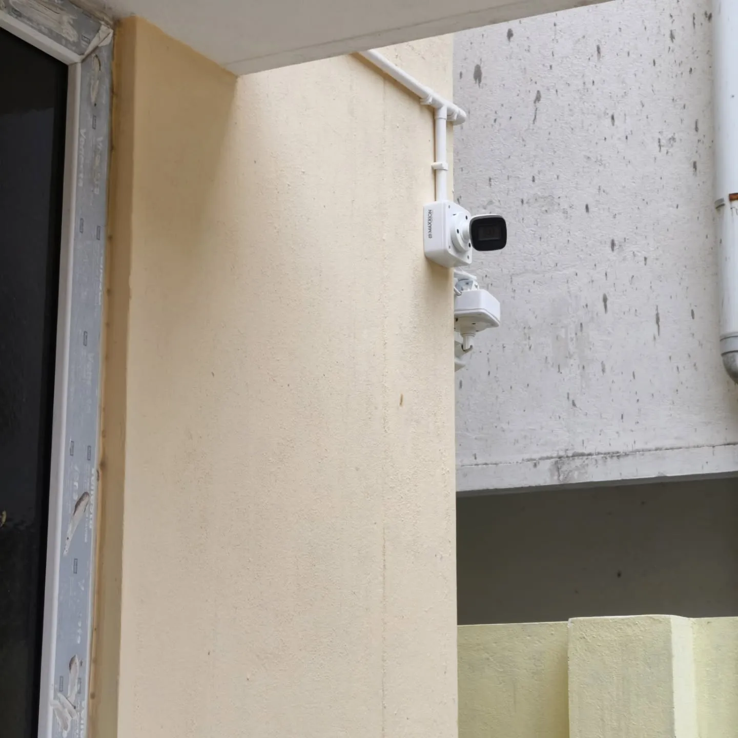 A Hikvision 5MP bullet security camera positioned under an exterior sunshade overhang with clean conduit lines.