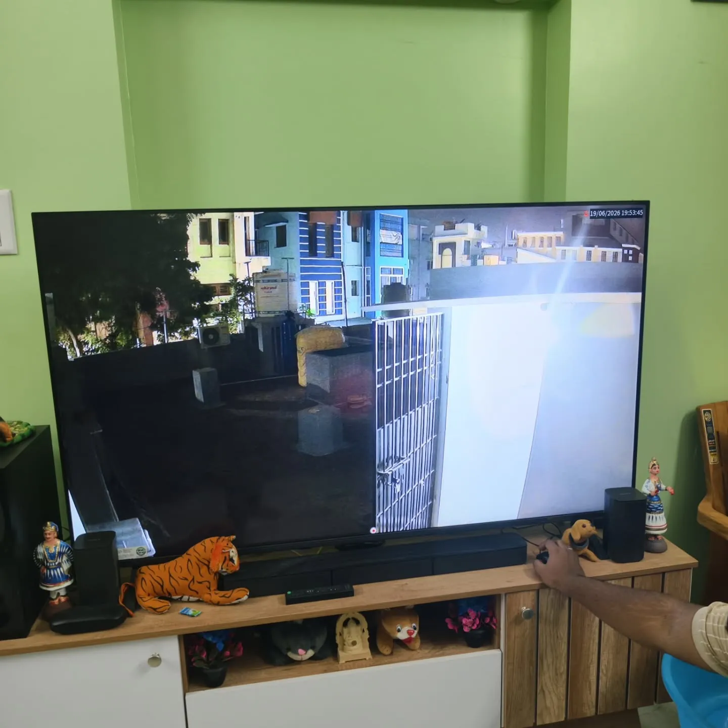 TV screen showing a Cpplus 2MP HD Dual Light camera feed monitoring a home terrace area, safety grill gate, and neighboring buildings.