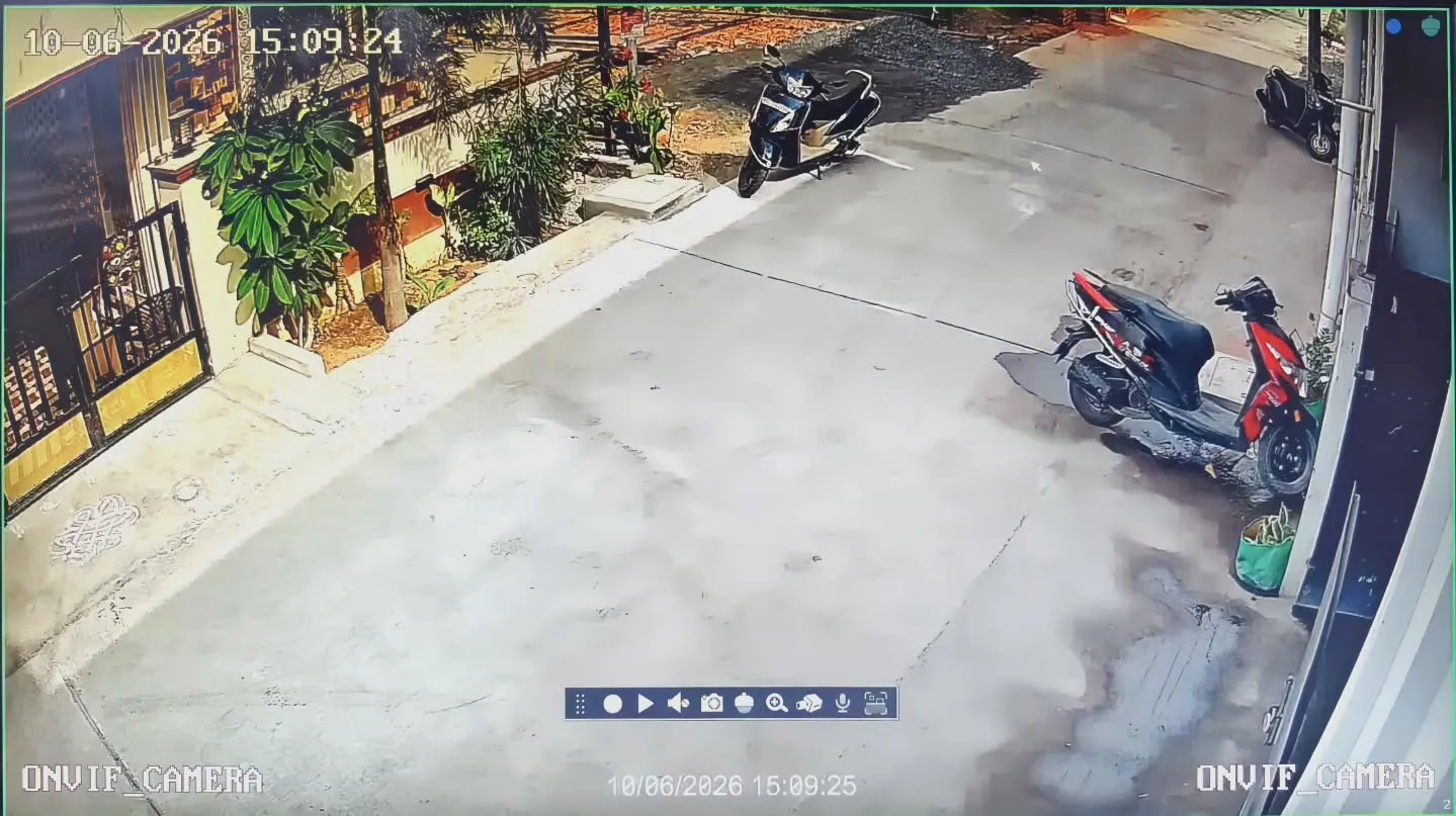 Wide-angle outdoor security footage from a Gopix 5MP IP camera installed at The Detailing Guru in Thandalam, displaying sharp 5-megapixel resolution coverage of the concrete approach lane, neighborhood entry gates, and parked scooters under clear daylight.