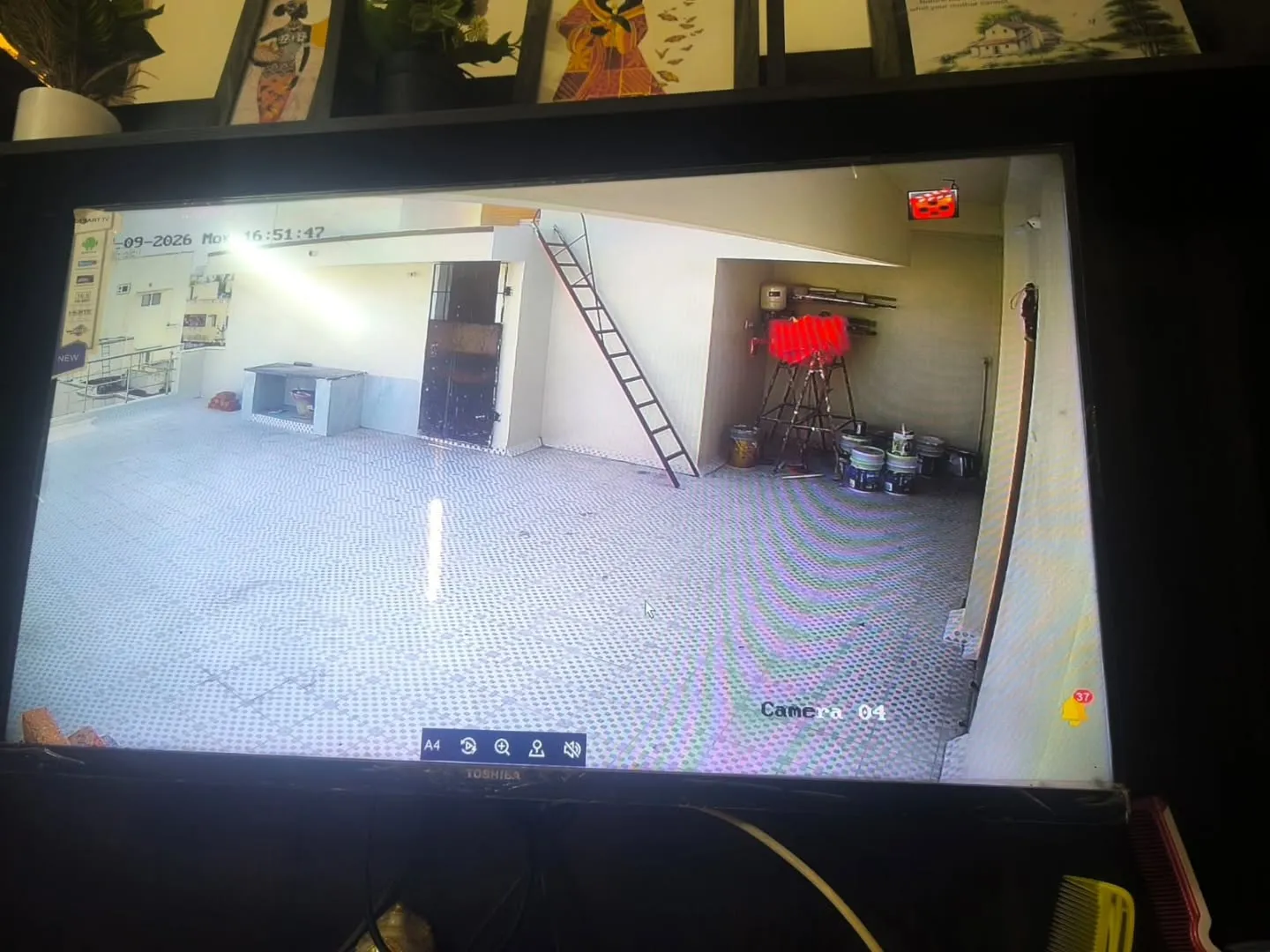 CCTV surveillance camera live angle showing open tiled courtyard parking and rear entry door of residential building