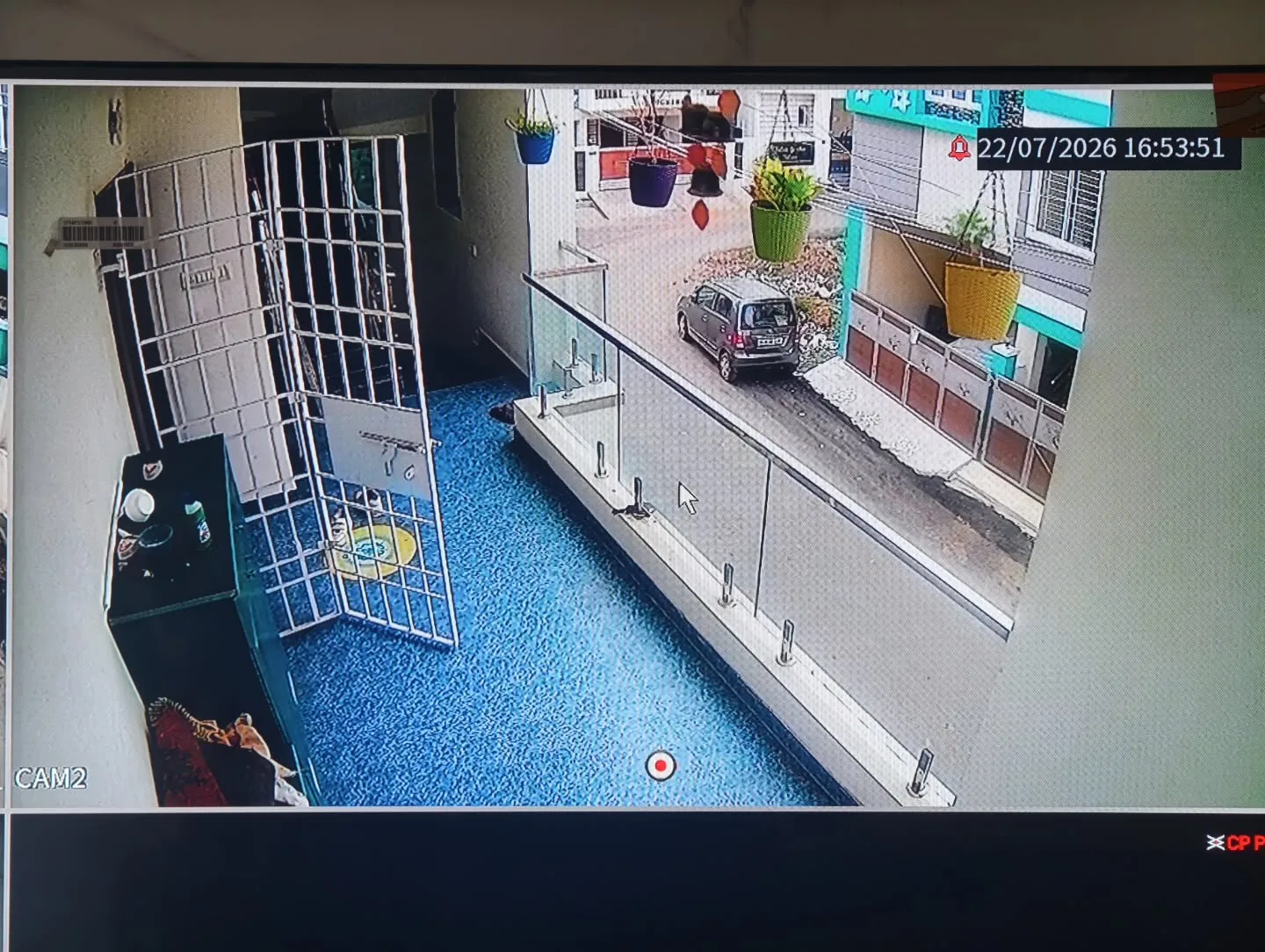 ​A crystal-clear monitor feed from a CP Plus 5MP dome camera overlooking the first-floor balcony area, safety grill, and glass railing perimeter.