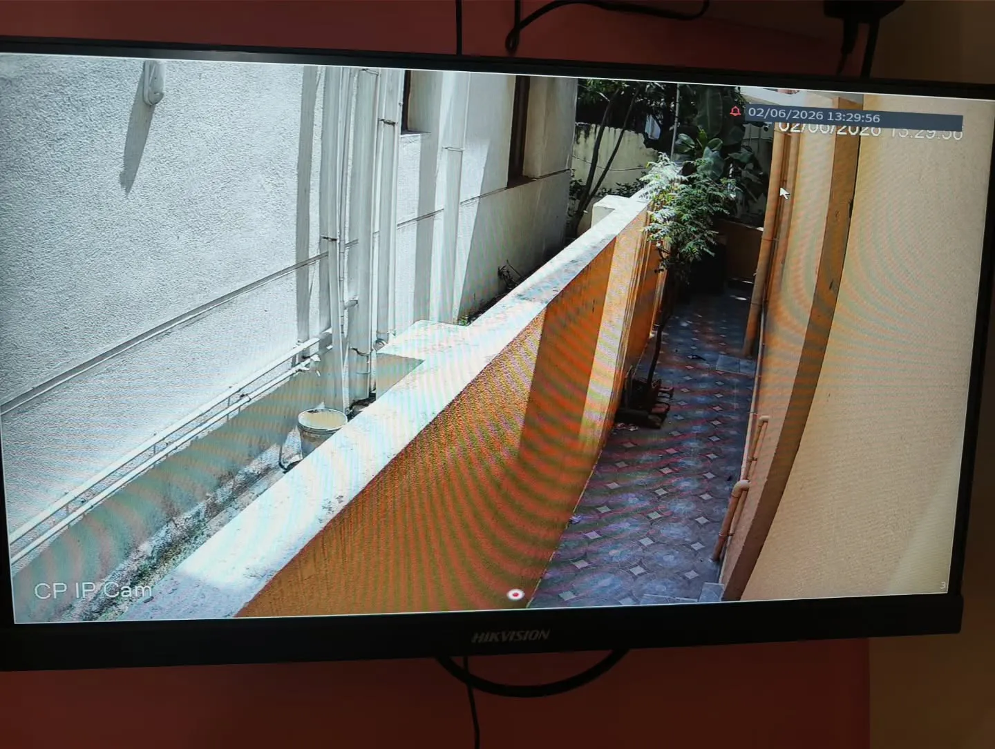 CP Plus 4MP STQC IP camera installation showing a live outdoor security feed of a residential building's narrow side pathway.