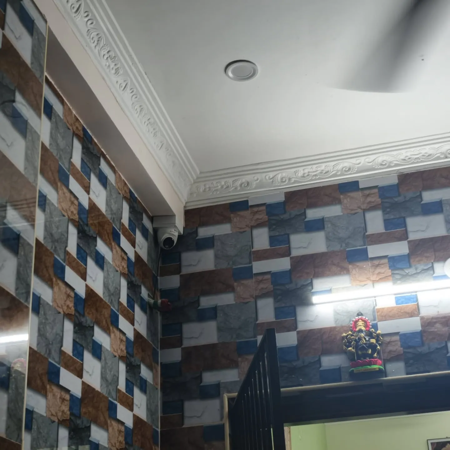 Corner-mounted Cpplus dome security camera positioned near a decorative tiled wall and ceiling border to monitor a home entrance.