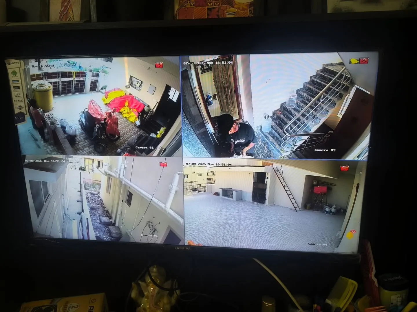 Hikvision 2MP 4 channel CCTV split screen monitor display showing residential parking, gate entrance, side walkway, and staircase in Keelkattalai Chennai
