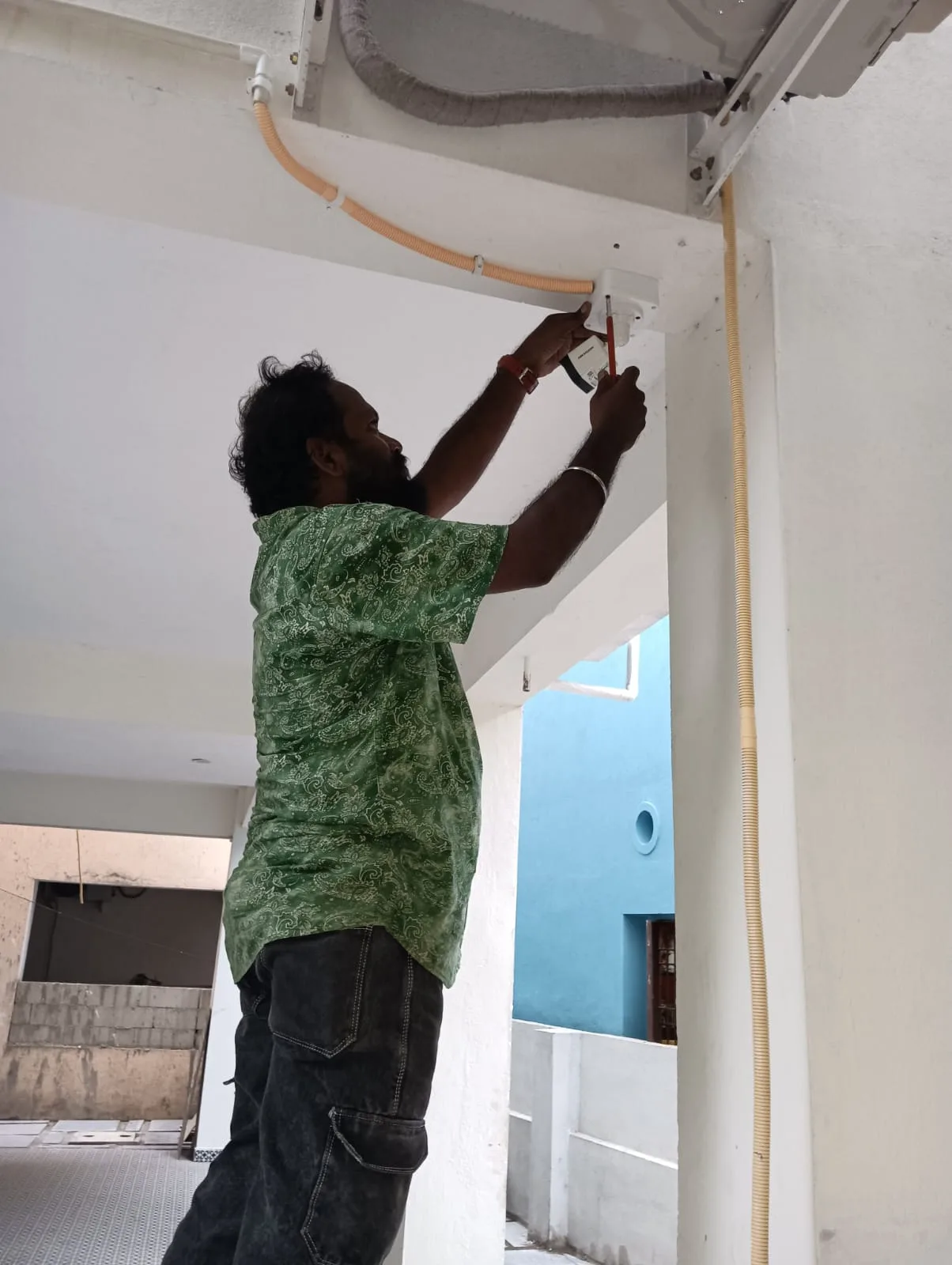 CCTV installation technician mounting a Hikvision 2MP bullet camera with waterproof junction box on a residential column in Nanganallur - View 1