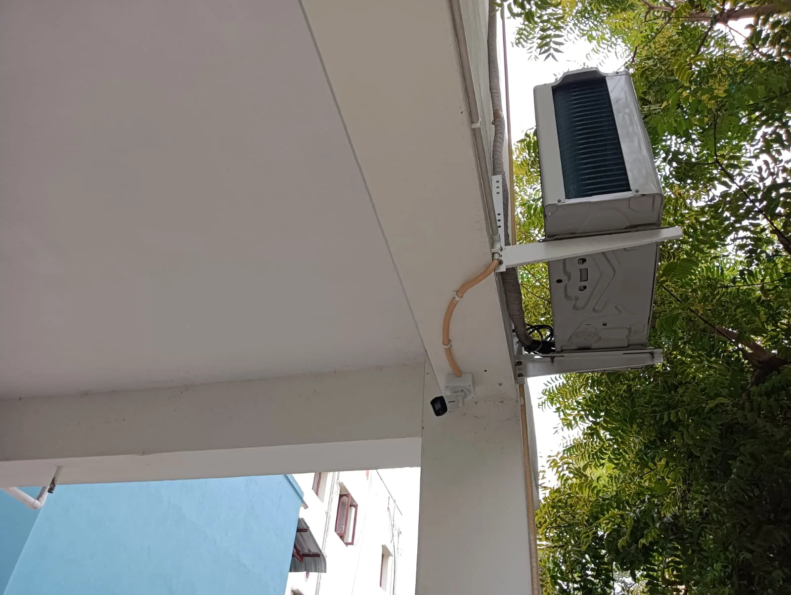 Hikvision outdoor bullet CCTV camera installed below AC outdoor unit using protective flexible conduit piping - View 2